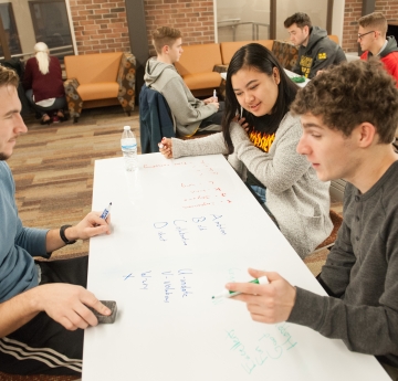 Two students sitting at a table with a tutor on the other side of the table